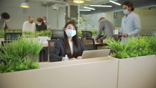 A beautiful lady is sitting in protective mask and looking to the camera — Stock Video