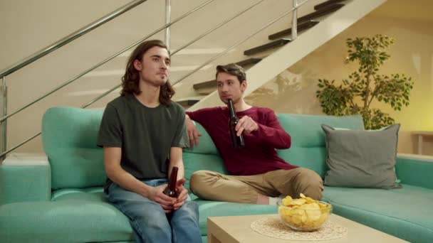 Dva přátelé pijí pivo a dívají se na televizi — Stock video