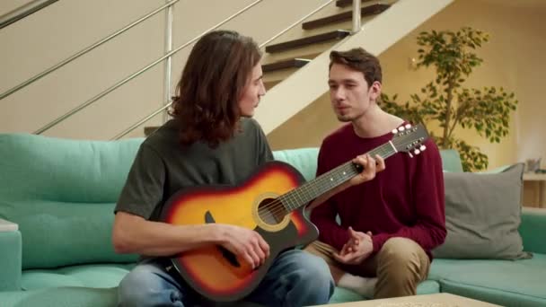 En ung man spelar gitarr för sin vän och båda sjunger. — Stockvideo