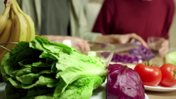 Un giovane uomo sta tagliuzzando un cavolo per un'insalata e parla — Video Stock