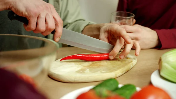 Un joven le está enseñando a su amigo cómo cortar pimienta bien fría. — Foto de Stock