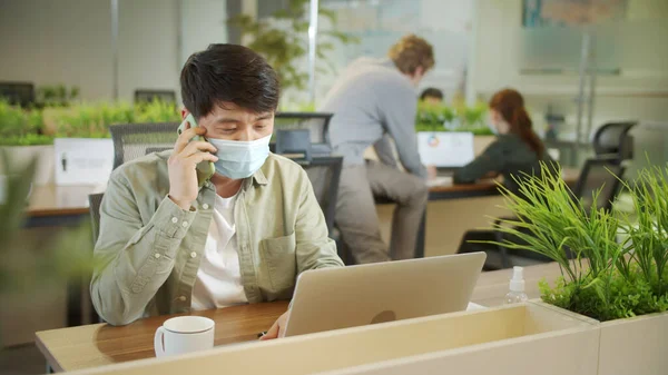 An adult businessman is talking with someone on the phone during working