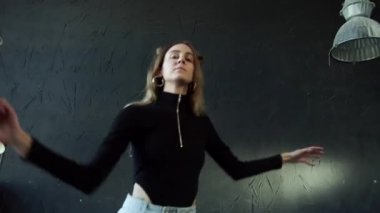 Okullu bir çocuk büyük bir odada serbest dans ediyor.