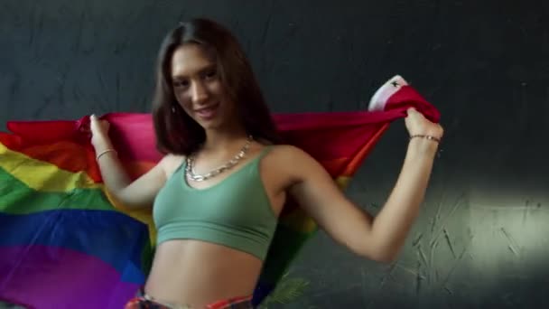 Jovem menina feliz está acenando bandeira orgulho LGBTQ — Vídeo de Stock