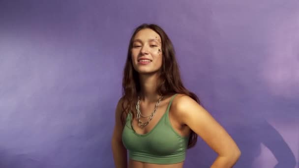 Una adolescente sonriente con el pelo moreno posa sobre un fondo morado — Vídeos de Stock