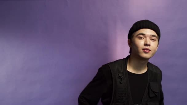 Porträt eines Teenagers mit schwarzem Hut auf lila Hintergrund — Stockvideo
