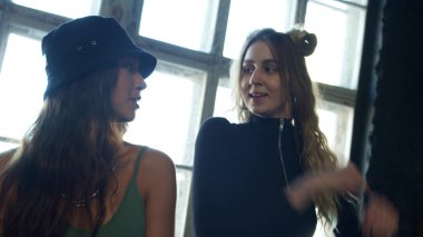 Küçük bir stüdyoda iki kız pencerenin kenarında dans ediyor. 