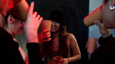 Gençler kulüpte kağıt bardaklarda içeceklerle dans etmekten hoşlanırlar.