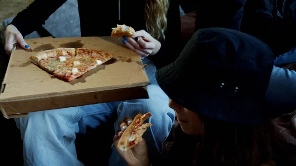 Jovens comendo pizza deliciosa sentados no sofá — Fotografia de Stock