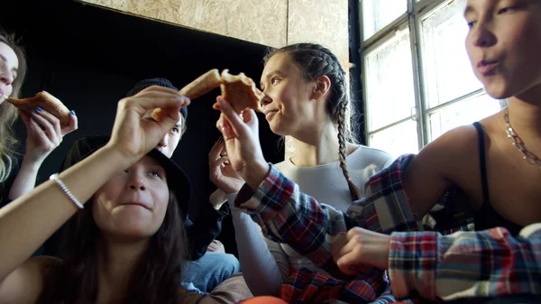 Adolescentes comem pizza juntos em um pequeno estúdio — Fotografia de Stock