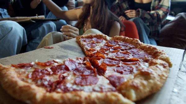 Young hipsters are sharing pepperoni pizza in a dance studio — Stock Photo, Image