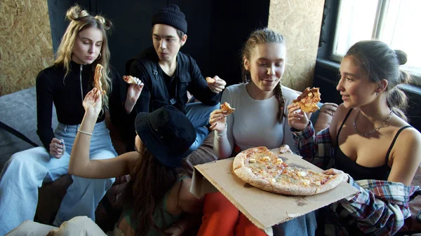 Groep tieners zitten op de bank om pizza te eten na een danspraktijk — Stockfoto