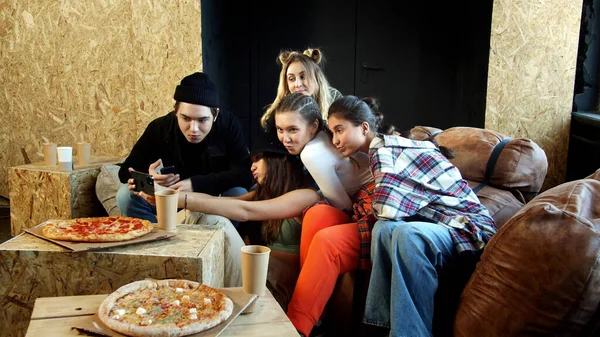Um grupo de jovens não tem pressa de comer pizza e tirar selfies — Fotografia de Stock