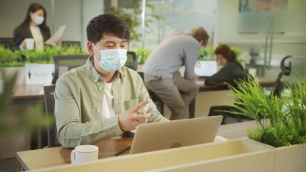 Een jonge collega zit in masker en reinigt zijn handen. — Stockvideo