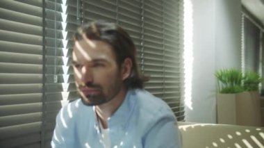 Genç ciddi bir adam kanepede oturuyor ve başka tarafa bakıyor.