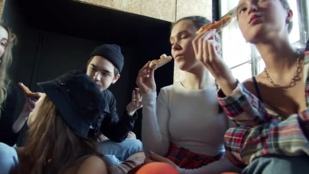 Młodzi faceci jedzą pizzę siedząc na kanapie — Wideo stockowe