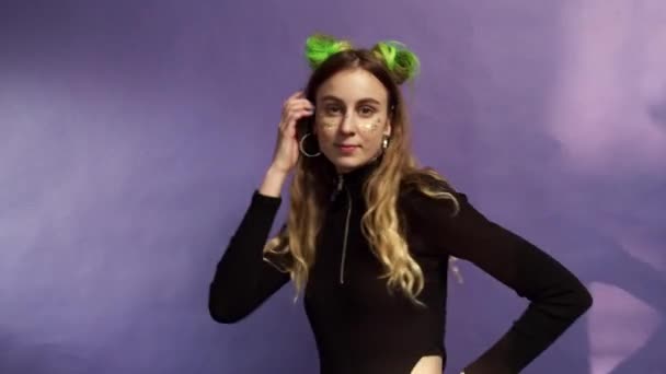 Młoda dziewczyna z zielonymi włosami i makijaż jest taniec na fioletowym tle — Wideo stockowe