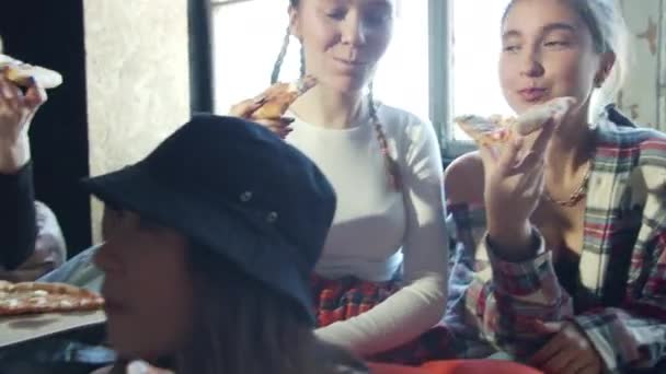 Glimlachende meisjes eten pizza met een vriend op de bank — Stockvideo