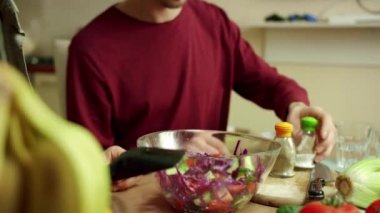 İki adam salataya biber ve tuz ekliyor.