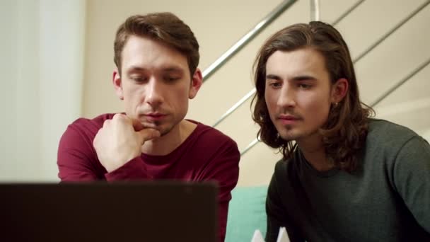 Twee vrienden zoeken iets op de laptop. — Stockvideo