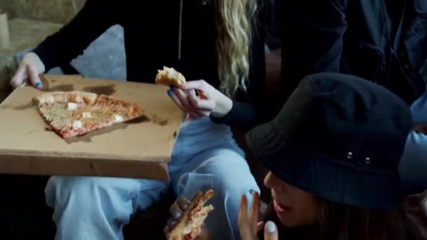Młodzi faceci jedzą pyszną pizzę siedząc na kanapie — Wideo stockowe
