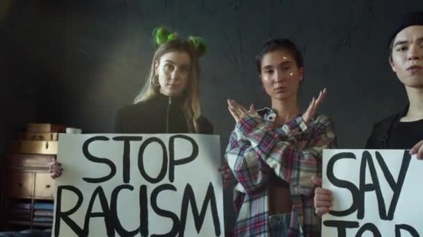 Dziewczyna pokazuje krzyż rękami, a inni trzymają sztandar rasizmu. — Wideo stockowe