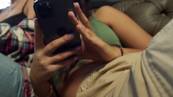 Jongeren zitten vast in telefoons die naast elkaar op de bank zitten. — Stockvideo