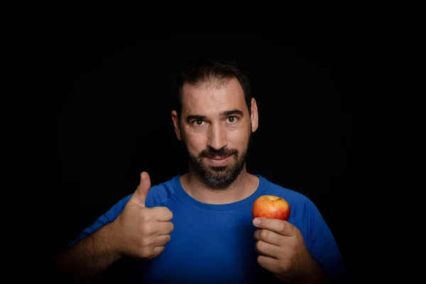 留着胡子的男人 身穿蓝色T恤 头戴黑色背景的苹果 健康饮食概念 — 图库照片