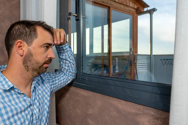 감정적으로 수염을 남자가 창문을 내다보고 걱정하고 우울하고 외롭게 보이죠 우울증 — 스톡 사진