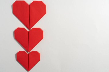 Sevgililer Günü 'nde beyaz arka planda aşık çiftler için renkli kağıtlardan yapılmış Origami kalpleri. Aşk konsepti