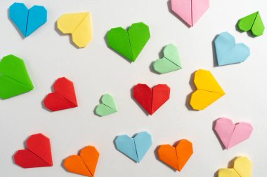 Sevgililer Günü 'nde beyaz arka planda aşık çiftler için renkli kağıtlardan yapılmış Origami kalpleri. Aşk konsepti