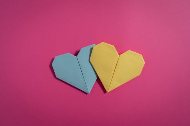 Sevgililer Günü 'nde birbirlerine aşık çiftler için pembe arka planda renkli kağıtlardan yapılmış Origami kalpleri. Aşk konsepti