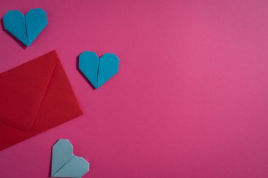 Sevgililer Günü 'nde birbirlerine aşık çiftler için pembe arka planda renkli kağıtlardan yapılmış Origami kalpleri. Aşk konsepti