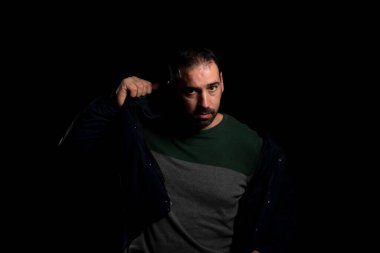 Çekici sakallı adam siyah arka planda yalnız poz veren mavi bir ceket giyiyor. Moda konsepti