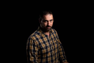 Siyah arka planda izole edilmiş sarı ekose gömlekli çekici sakallı adam. Moda konsepti