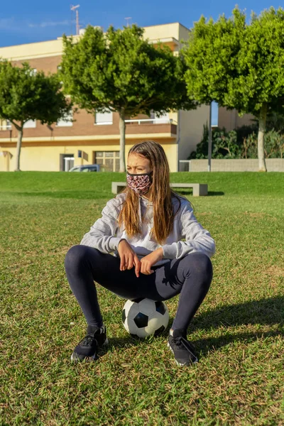 Krásná Holčička Sedí Vrcholu Fotbalového Míče Nosí Masku Aby Chránila — Stock fotografie