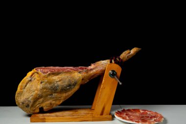 Detail of ham placed in a wooden ham holder ready to be cut. Exquisite food. Spanish tradition. Feeding concept clipart