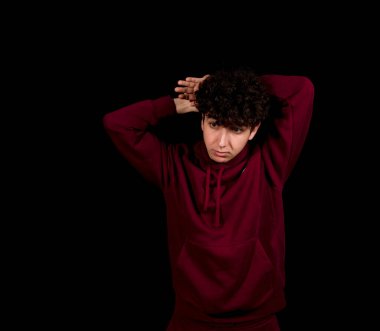 Siyah arka planda poz veren kıvırcık saçlı çekici bir genç. Moda konsepti