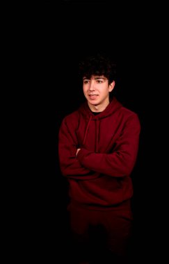 Siyah arka planda poz veren kıvırcık saçlı çekici bir genç. Moda konsepti