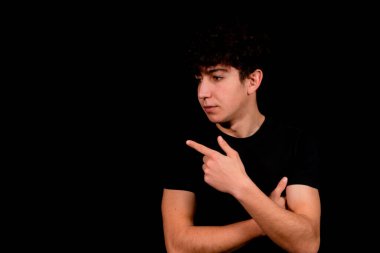 Siyah arka planda poz veren kıvırcık saçlı çekici bir genç. Moda konsepti