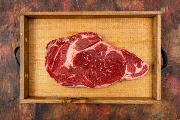 Ribeye Ternera Cruda Una Vieja Bandeja Madera Sobre Una Tabla —  Fotos de Stock