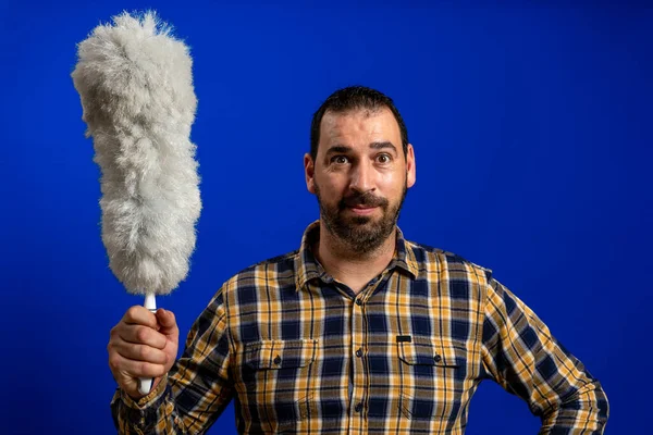 青いスタジオの背景に掃除ダスターで面白いポーズをとる素敵な髭の男 清掃コンセプト — ストック写真