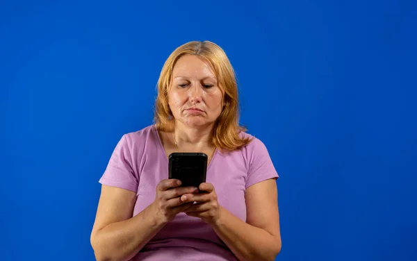 Ganska Medelålders Kvinna Använder Sin Smartphone Mycket Allvarlig Isolerad Blå — Stockfoto