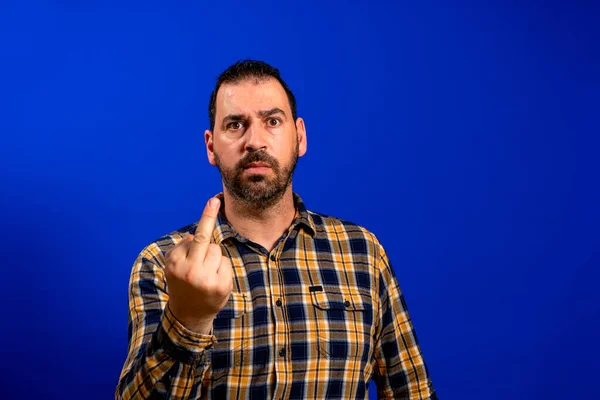 Man wearing casual t-shirt standing over blue isolated background Showing middle finger, impolite and rude fuck off expression — ストック写真