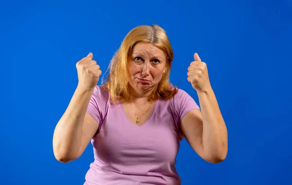 Donna di mezza età in piedi sopra sfondo blu isolato arrabbiato e pazzo alzando pugni frustrato e furioso mentre gridava con rabbia. Rabbia e concetto aggressivo. — Foto Stock