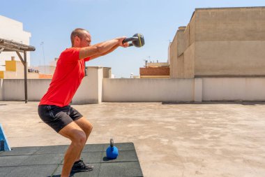 Kettle Bell tutan kaslı üstsüz bir adam ve dışarıda ağırlık antrenmanına hazırlanıyor. Eğitim kavramı