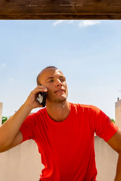 Atractivo joven caucásico hombre hablando con su teléfono inteligente al aire libre. Concepto tecnológico — Foto de Stock