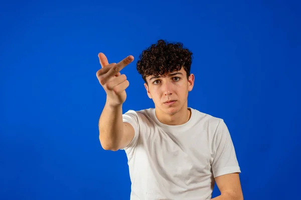 Portrait of a young man showing middle finger gesturing fuck isolated on blue background. Gesture concept — Stok fotoğraf