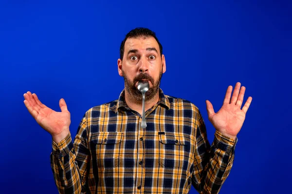 Close-up portret van aantrekkelijke sceptische man likken lepel gezonde menu voeding geïsoleerd over helder blauwe kleur achtergrond — Stockfoto