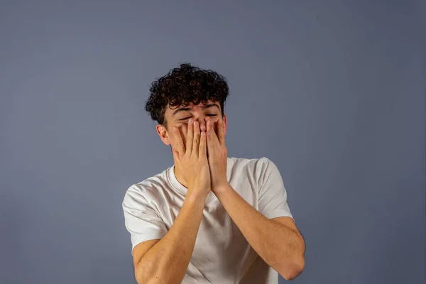 Joven hombre guapo con camiseta casual sobre fondo gris aislado mirando estresado y nervioso con las manos en la boca mordiendo las uñas. Problema de ansiedad. — Foto de Stock